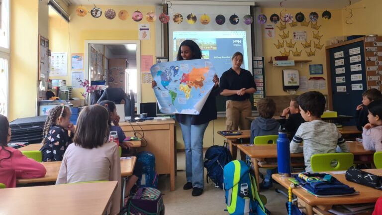 Lehrer hält Weltkarte und unterrichtet aufmerksame Schüler in einem lebhaften Klassenzimmer.