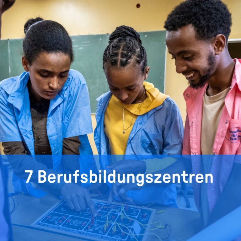Drei junge Leute arbeiten an einem Tisch gemeinsam an einem Elektronikprojekt.
