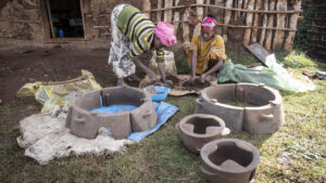 Zwei Frauen formen draußen Tonöfen.