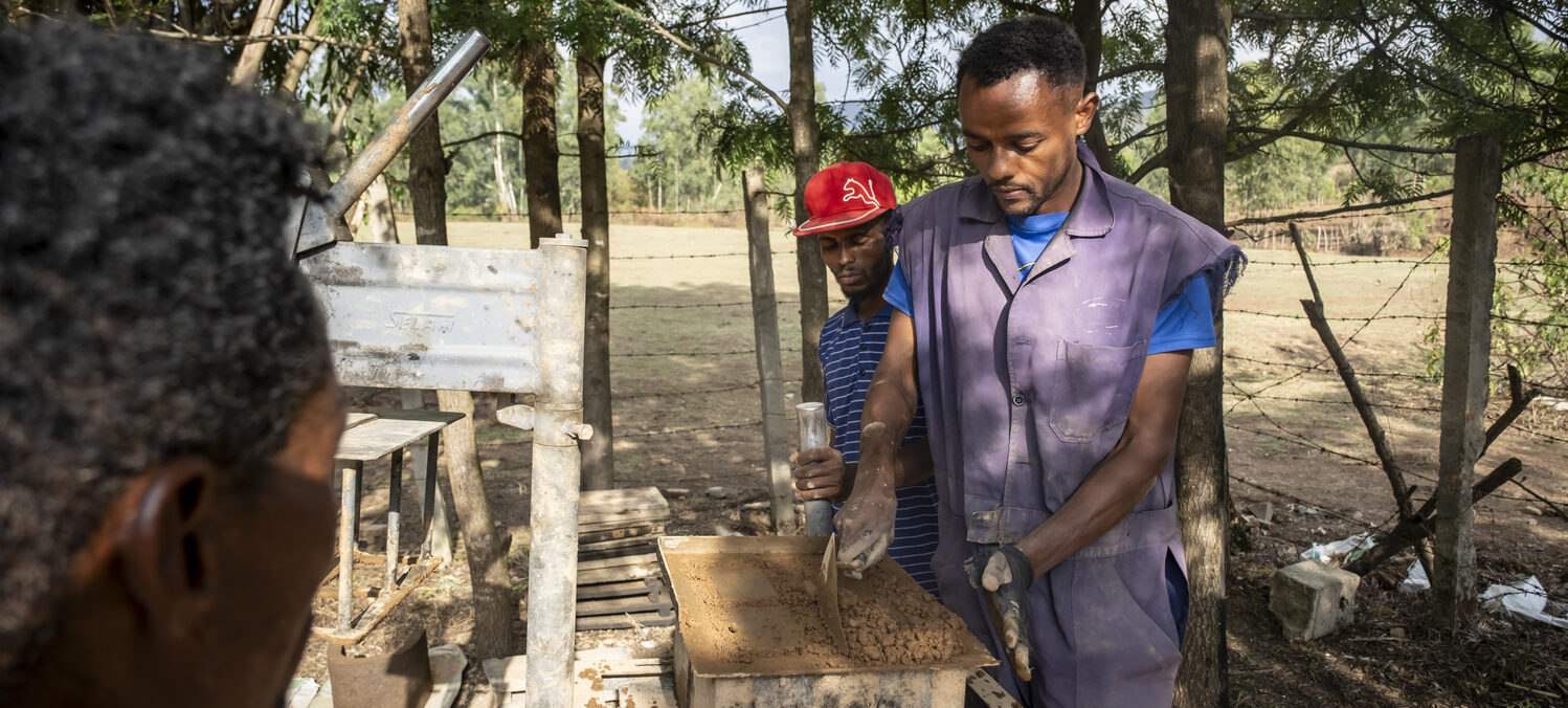 Zwei junge Männer bei der Herstellung von Blocksteinen.