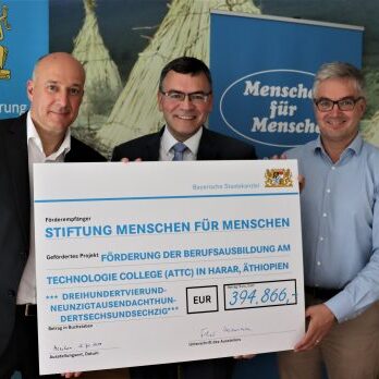 Drei Männer überreichen einen Spendenscheck in Höhe von 394.866 Euro an eine äthiopische Berufsschule.
