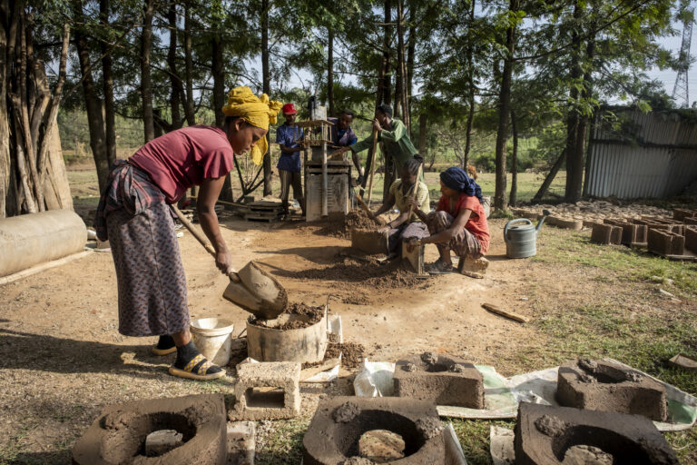 Frauen stellen in Handarbeit holzsparende Öfen her.