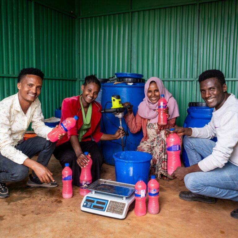 Zwei Männer und zwei Frauen halten rosafarbene Seife in den Händen, die sie selbst hergestellt haben und verkaufen werden.