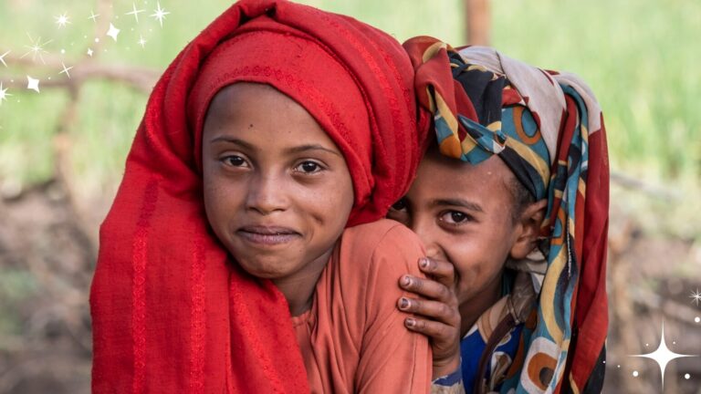 Auf dem Bild sieht man zwei kleine Mädchen aus Äthiopien, die verschmitzt in die Kamera lachen. Es strahlt menschliche Wärme und Zusammenhalt aus, was das Motto der Weihnachtskampagne von Menschen für Menschen ist.