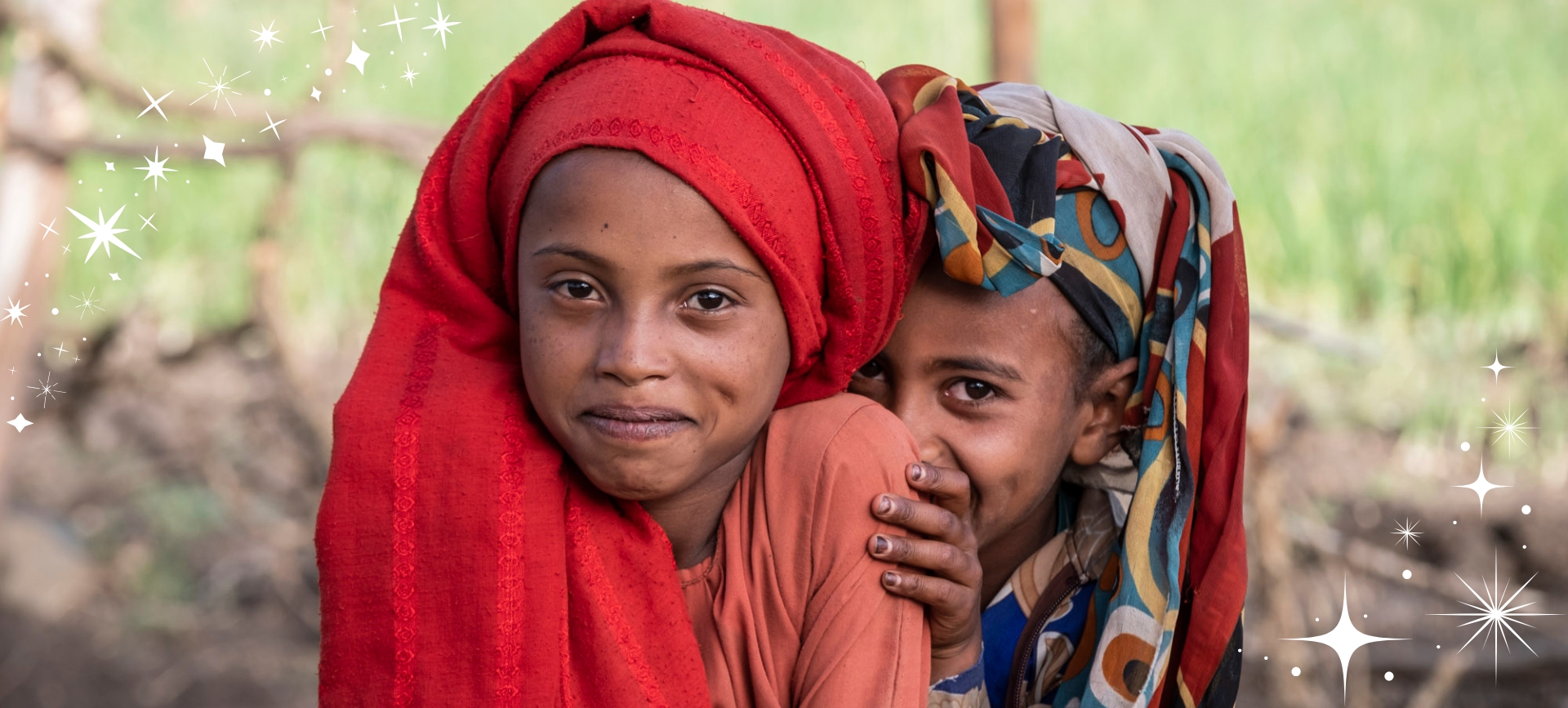 Auf dem Bild sieht man zwei kleine Mädchen aus Äthiopien, die verschmitzt in die Kamera lachen. Es strahlt menschliche Wärme und Zusammenhalt aus, was das Motto der Weihnachtskampagne von Menschen für Menschen ist.