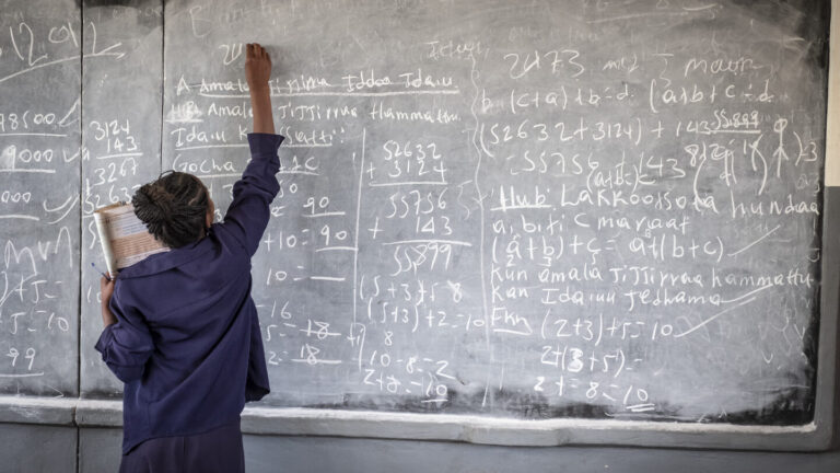 Eine Schülerin schreibt während des Unterrichts an die Tafel.