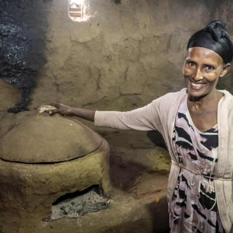 Eine Frau zeigt ihren holzsparenden Ofen in ihrem Wohnhaus.