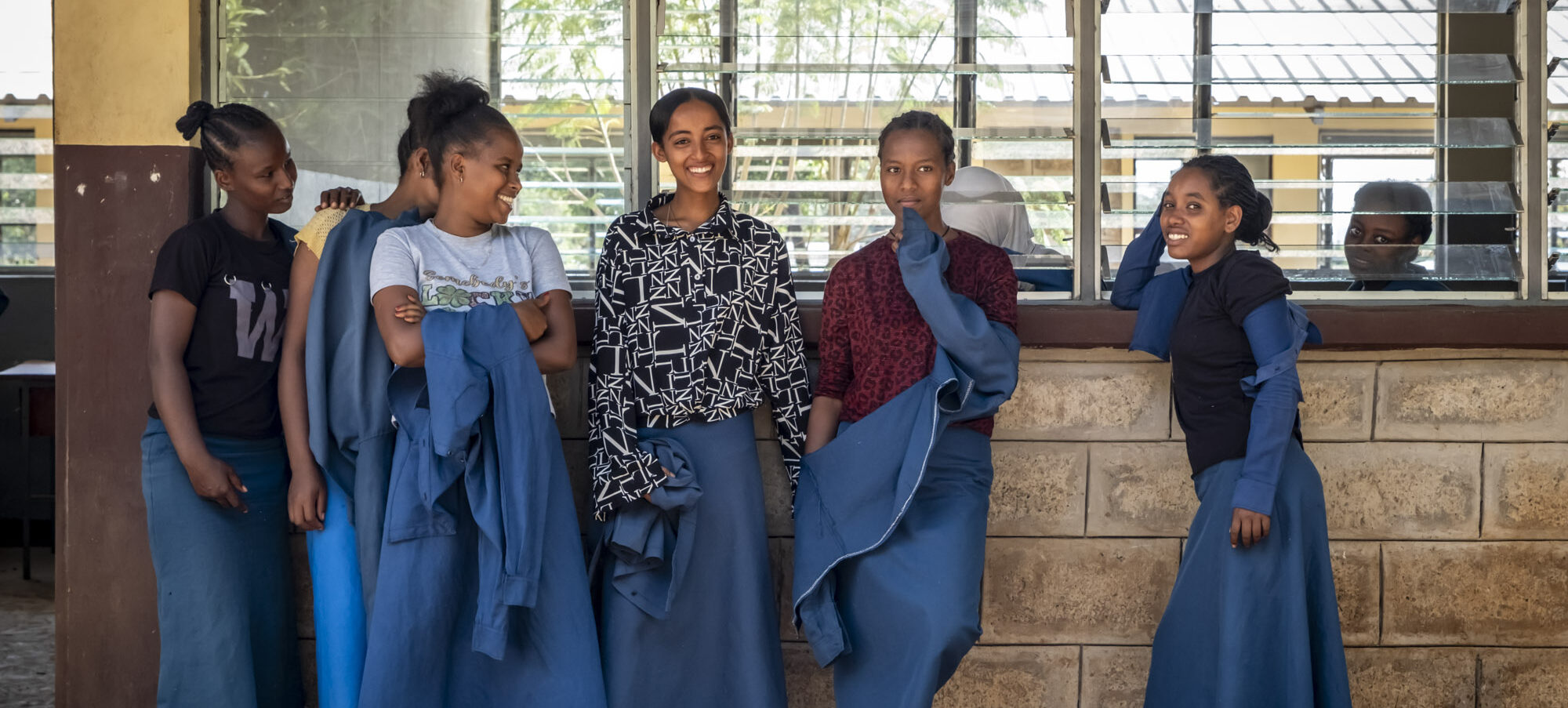 Eine Gruppe von Schülerinnen steht vor einem hellen Schulgebäude.