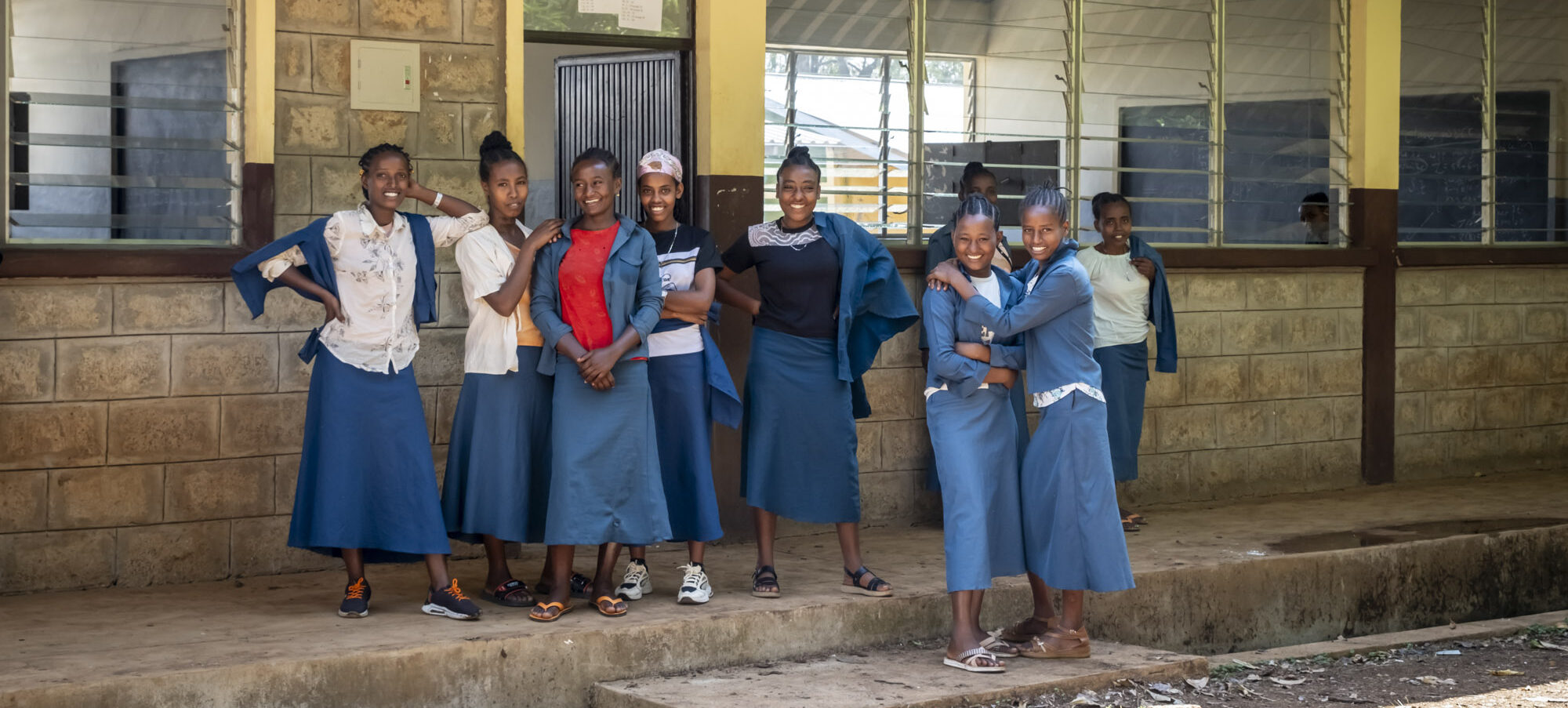 Schülerinnen und Schüler stehen vor ihrer neu gebauten Schule.