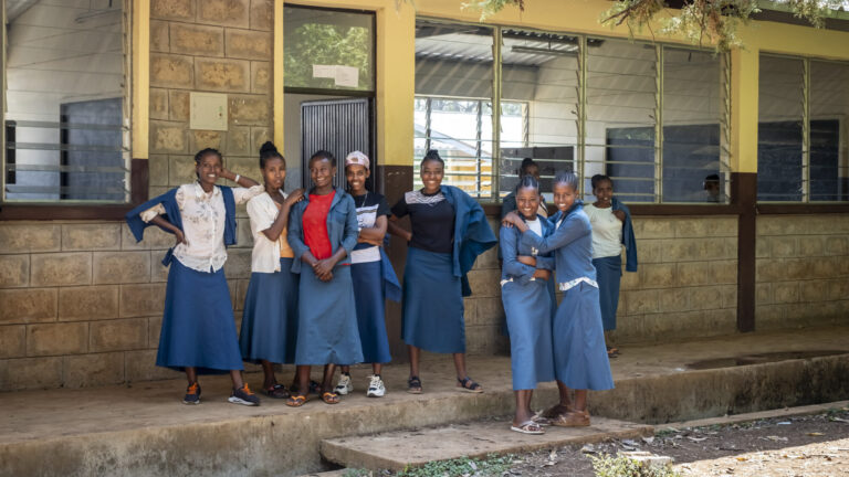 Schülerinnen und Schüler stehen vor ihrer neu gebauten Schule.