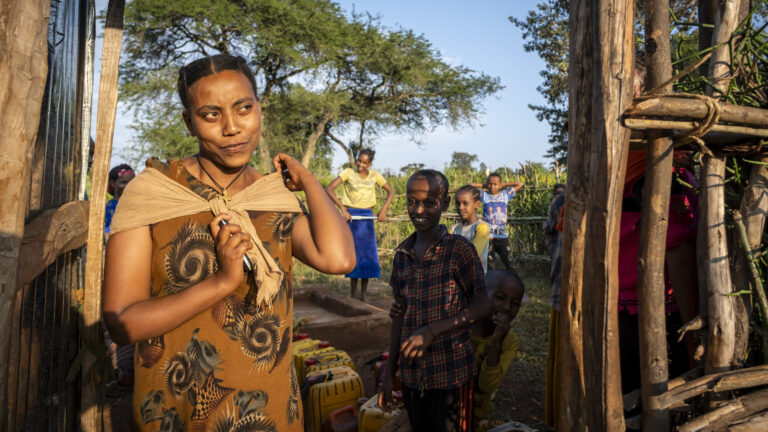 Frauen holen an einem neu gebauten Brunner frisches Trinkwasser.