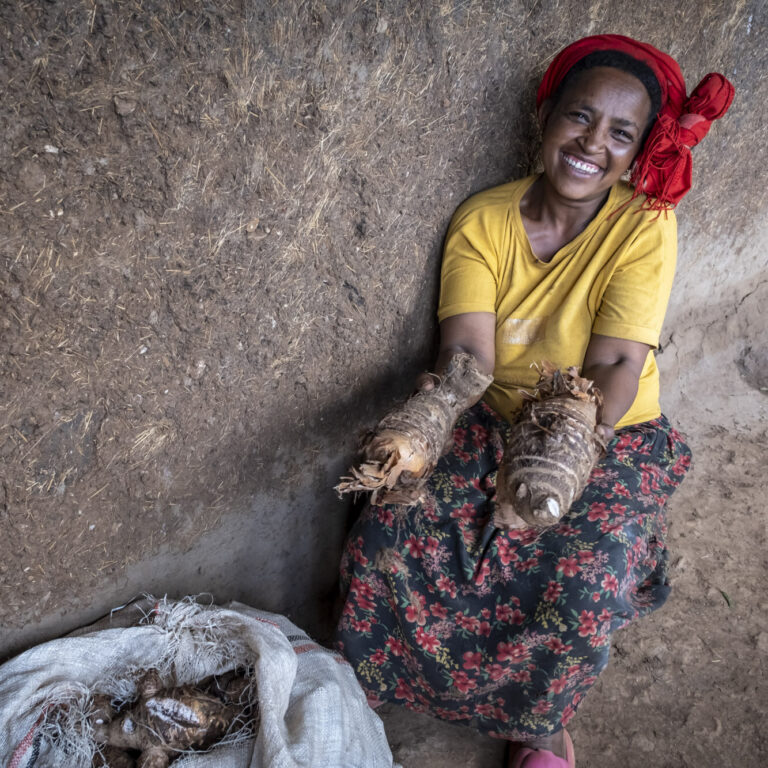 Eine Farmerin zeigt stolz ihre frisch geernteten Süßkartoffeln.