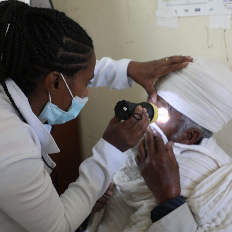 Eine Augenärztin untersucht einen Mann, der an Katarakt erkrankt ist.