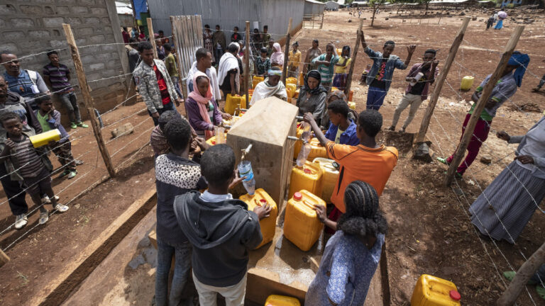 Eine Gruppe von Personen die Wasser an einer neugebauten Wasserstelle holen.