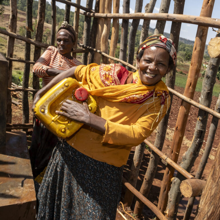 Eine Frau trägt einen gelben Wasserkanister unter ihrem Arm.