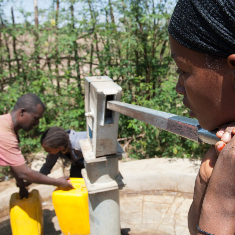 Mädchen pumpt Wasser aus Brunnen