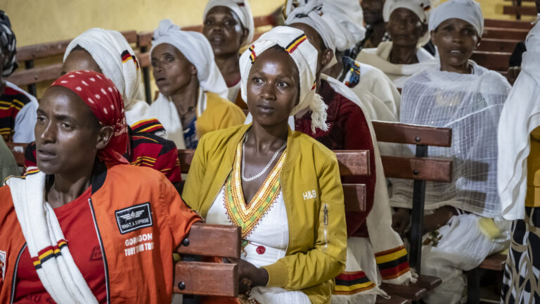 Eine Frau sitzt auf einer Bank und hört einem Workshop zu.