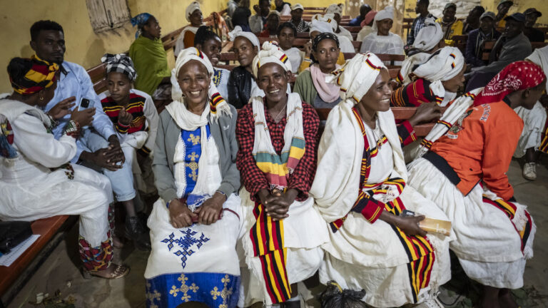 Ein Workshop Raum voller Frauen die auf Bänken sitzen und lächeln.