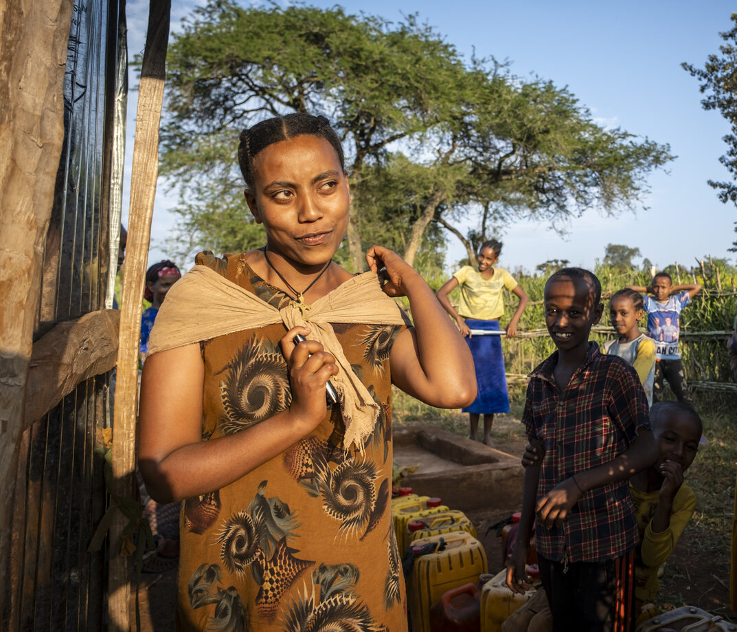 Eine junge Frau bindet sich einen vollen Wasserkanister auf den Rücken.