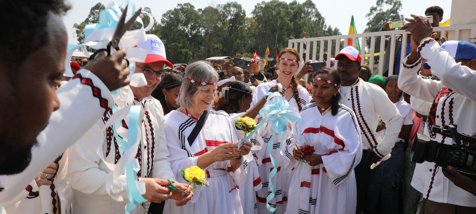 TVET Eröffnung. Man sieht Personen in weißem Gewand feiern.