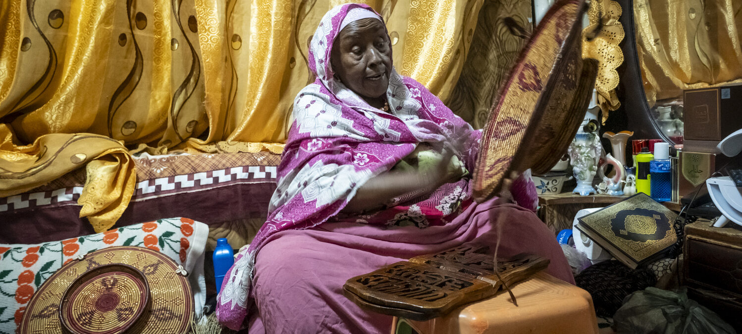 Harari-Händlerin Fatuma webt einen bunten Korb.