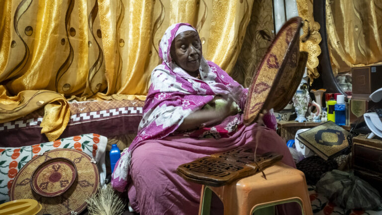 Harari-Händlerin Fatuma webt einen bunten Korb.
