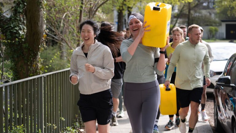 Eine Gruppe an Läufern mit Wasserkanistern