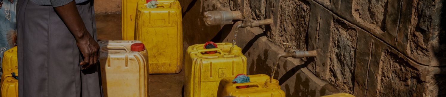 Gelbe Kanister werden mit Wasser an einer Wasserstelle gefüllt.