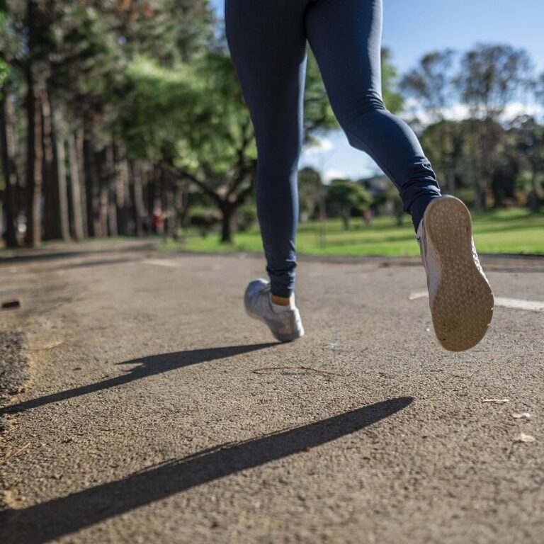 Person, die auf einem Weg im Park läuft. Man sieht die Beine.
