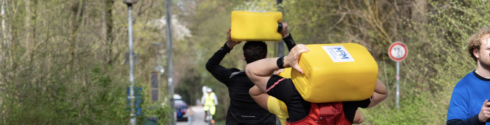 Mehrere Menschen mit Wasserkanister auf Rücken.