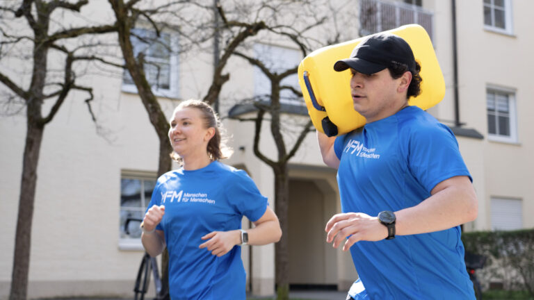 Mann trägt Wasserkanister.