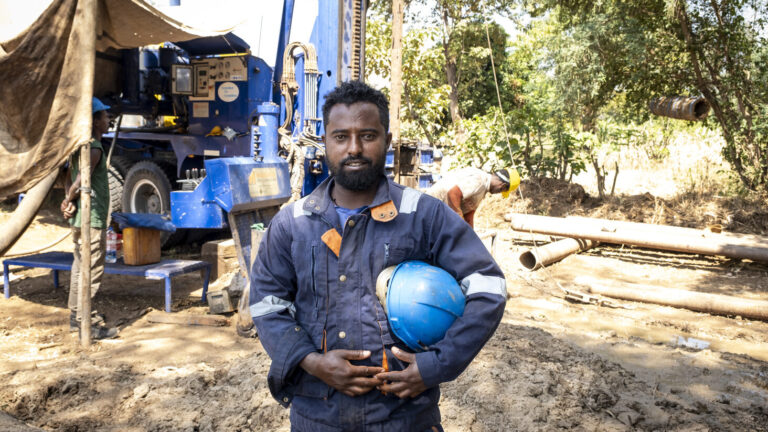 Ein Bohrmeister für eine Brunnenbau steht vor der Bohrmaschine.