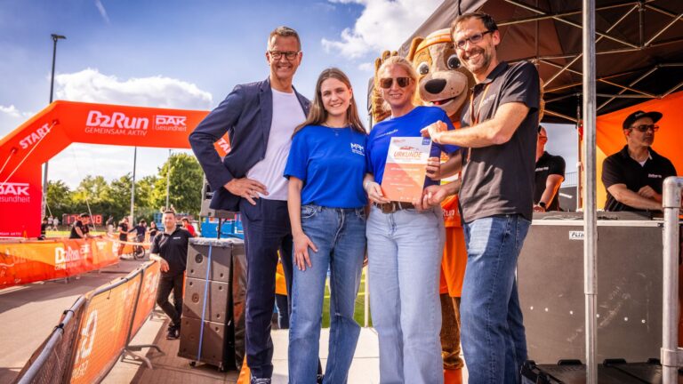 Zwei Männer, zwei Frauen, die auf einem Podest stehen und eine Urkunde in die kamera halten. Beim B2Run.