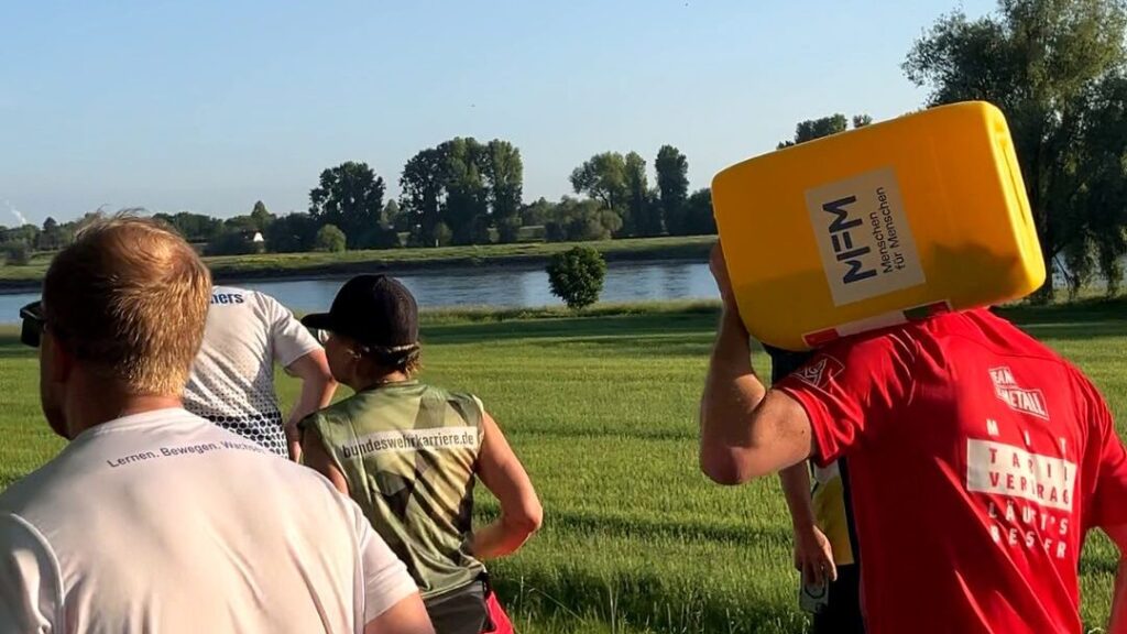 Männer, die mit einem Wasserkanister bei einem Lauf joggen.