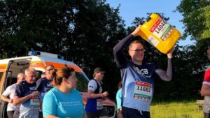 Männer, die mit einem Wasserkanister bei einem Lauf joggen.