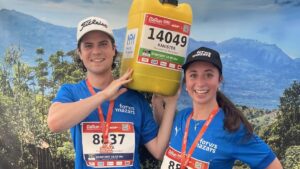 Ein Mann und eine Frau in Laufklamotten posieren mit einem gelben Wasserkanister.
