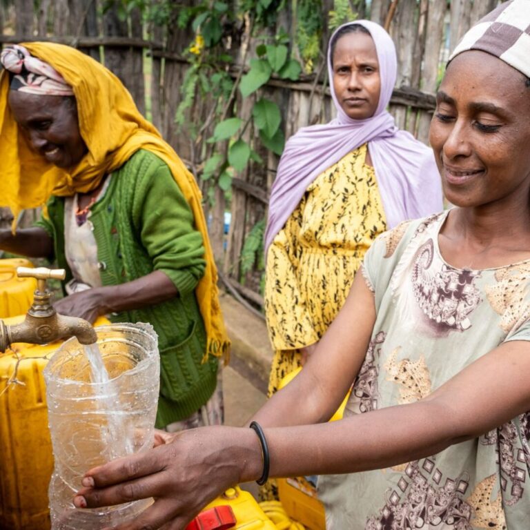 Frauen die sauberes Wasser abfüllen