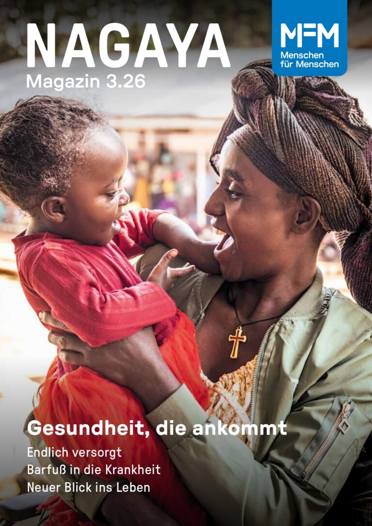 Eine Mutter hält ihre kleine Tochter auf dem Arm und beide lachen sich an.