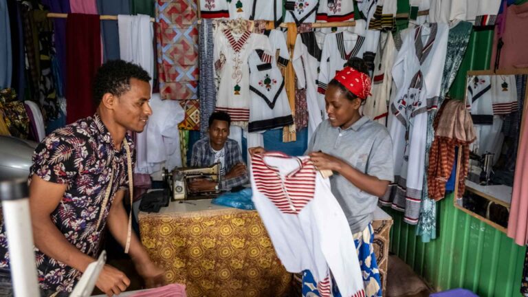 Projektgebiet Illu Gelan. Oromo Feiertag, traditionelle Kleider. Dejene Bijiga, 23 (buntes Hemd), arbeitet als Schneider in Ijaji. Dejene Mulisa, 35 kauft bei ihm ein.
