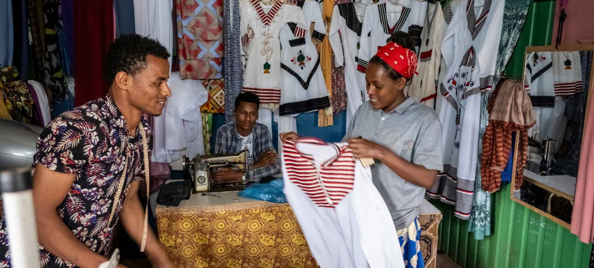 Projektgebiet Illu Gelan. Oromo Feiertag, traditionelle Kleider. Dejene Bijiga, 23 (buntes Hemd), arbeitet als Schneider in Ijaji. Dejene Mulisa, 35 kauft bei ihm ein.