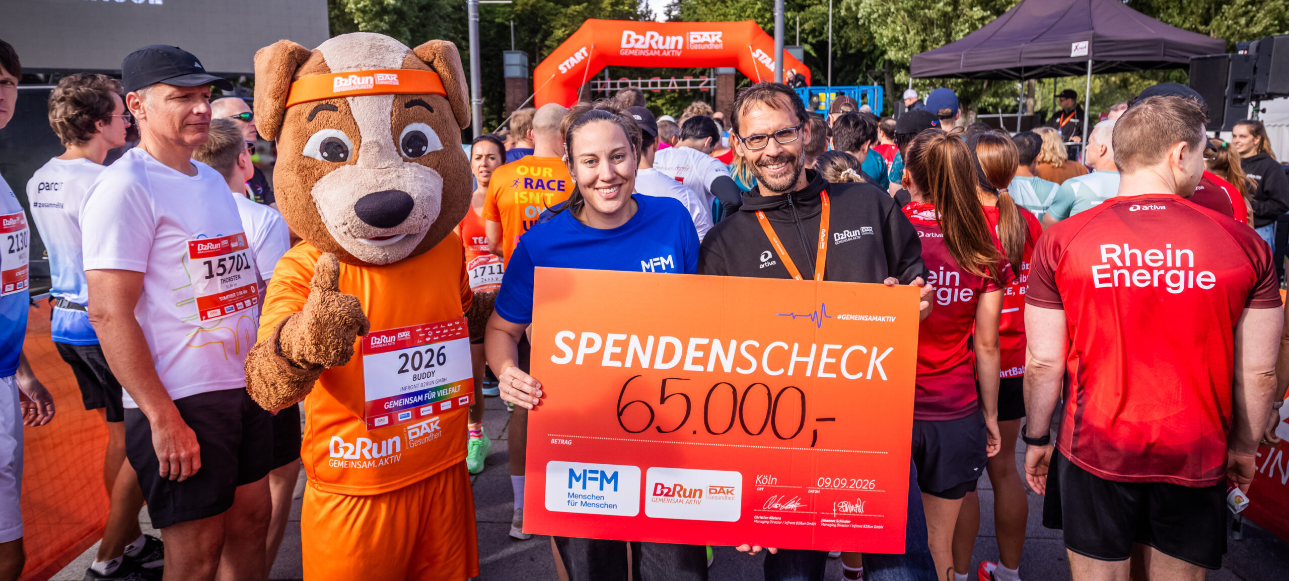Überreichen des Spendenschecks in Höhe von 65.000€ mit MFM Mitarbeiter, B2Run Mitarbeiter und Maskottchen.